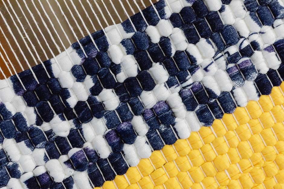 Close-up view of a handmade textile rug woven on a loom with vibrant colors.